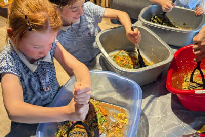 Children are mashing up food items inside washing buckets, modelling the first step of the digestive system in the mouth. 